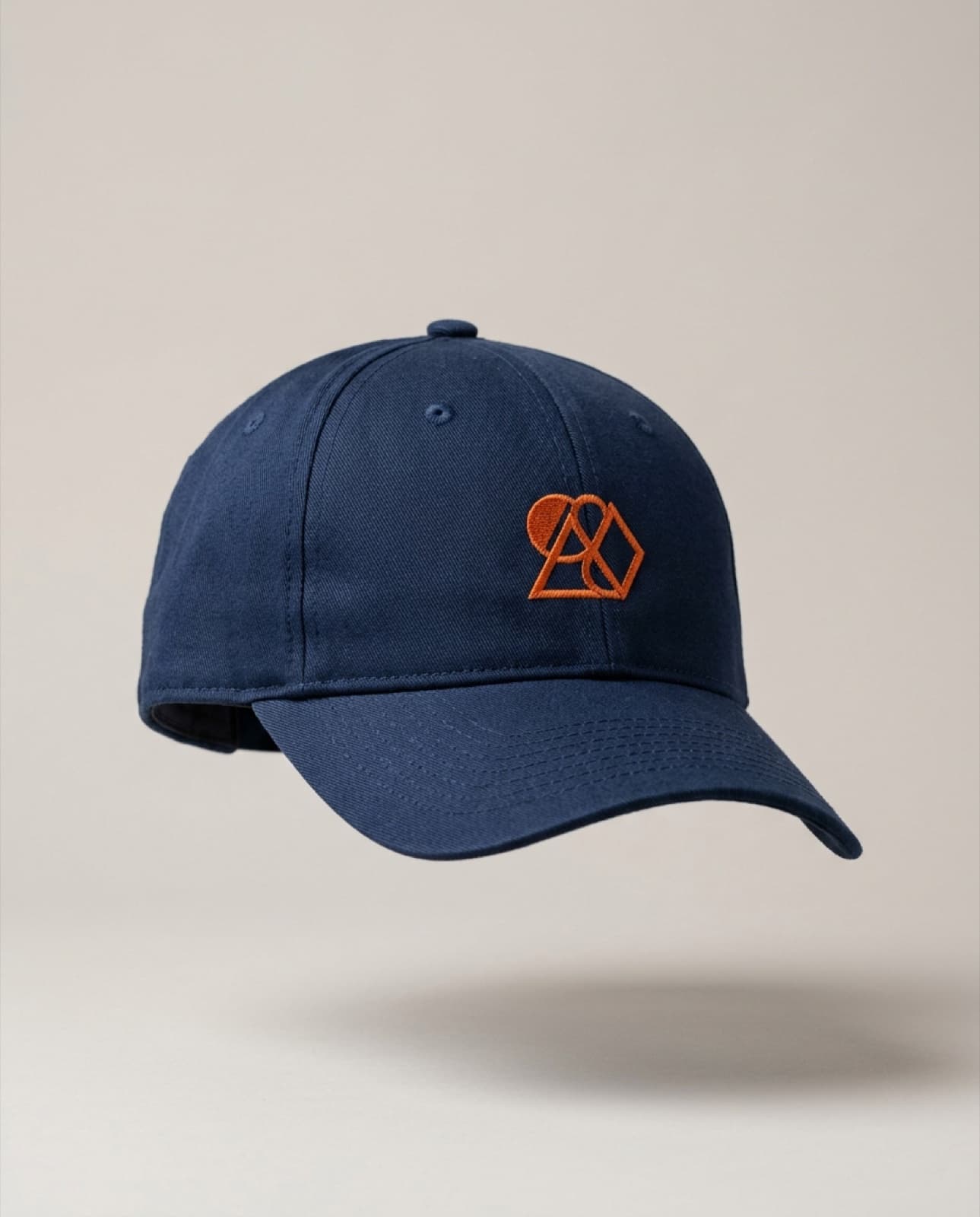 Gorra azul marino de 6 paneles con emblema bordado naranja (imagen ilustrativa)