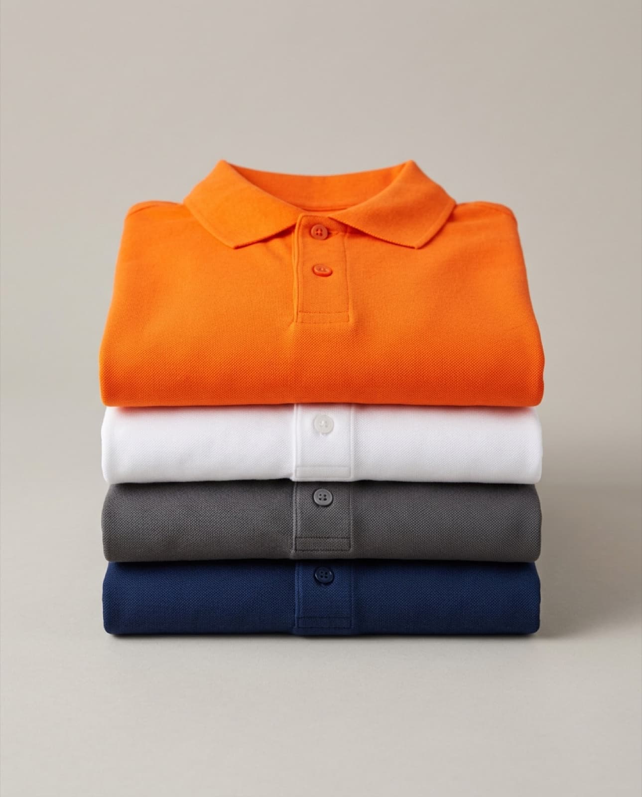 Polos piqué doblados en azul marino, gris, blanco y naranja, colores corporativos (imagen ilustrativa)